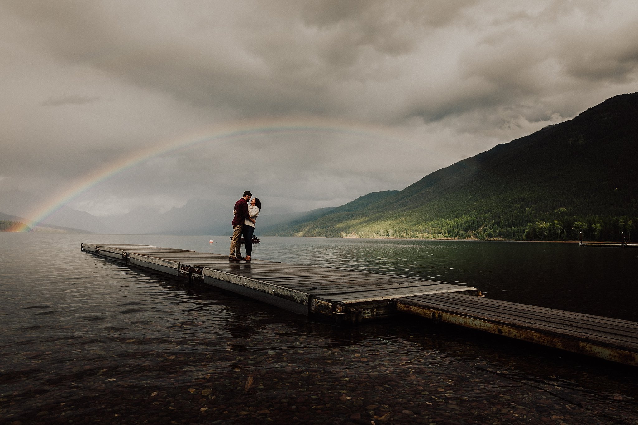 Stormy Lake McDonald Engagement photos with rainbow over the lake